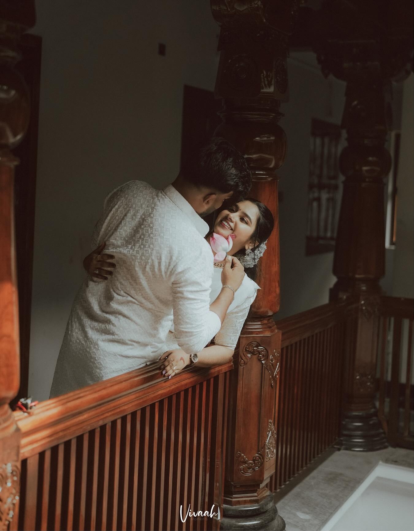 A couple embracing beside a carved wooden staircase